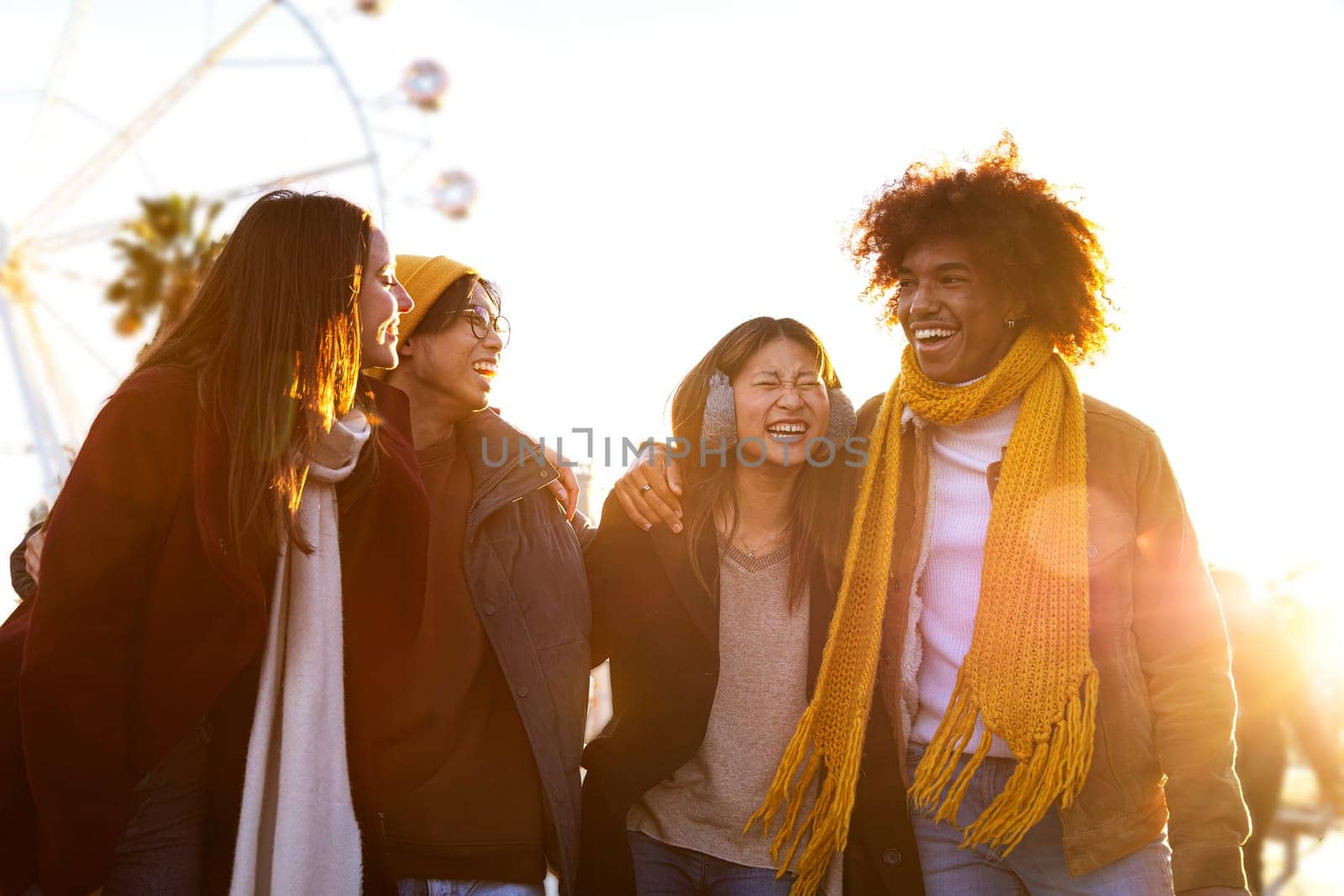 Group of friends laughing while embracing and walking together on sunny winter day in the city. Friendship and lifestyle concept.