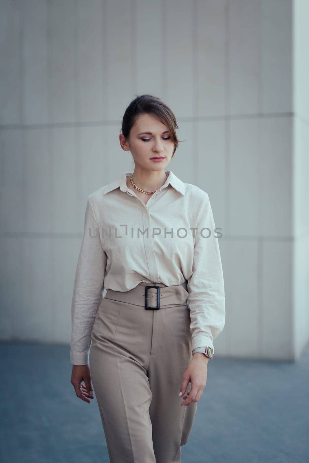 Young caucasian business woman in office fashion style suit in beige tones walking towards the camera.