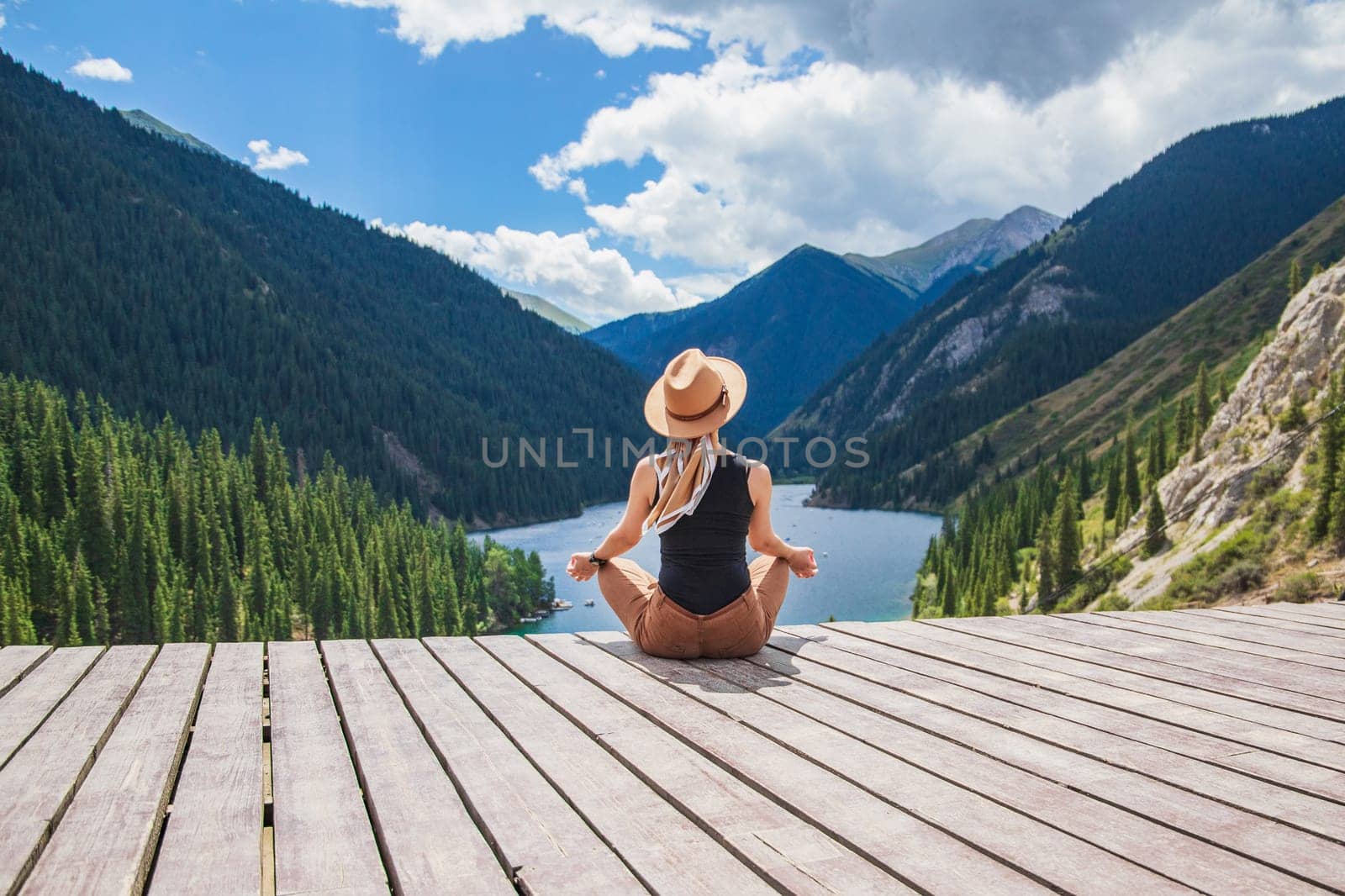 Beautiful woman relaxing on Kolsay Lake in Kazakhstan mountains. Nature of Central Asia, domestic tourism, vacation concept.