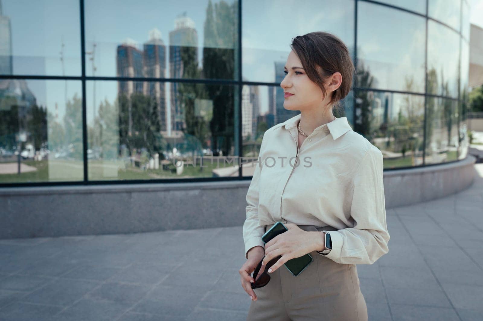 Caucasian young woman in a business suit on the background of an office modern building.