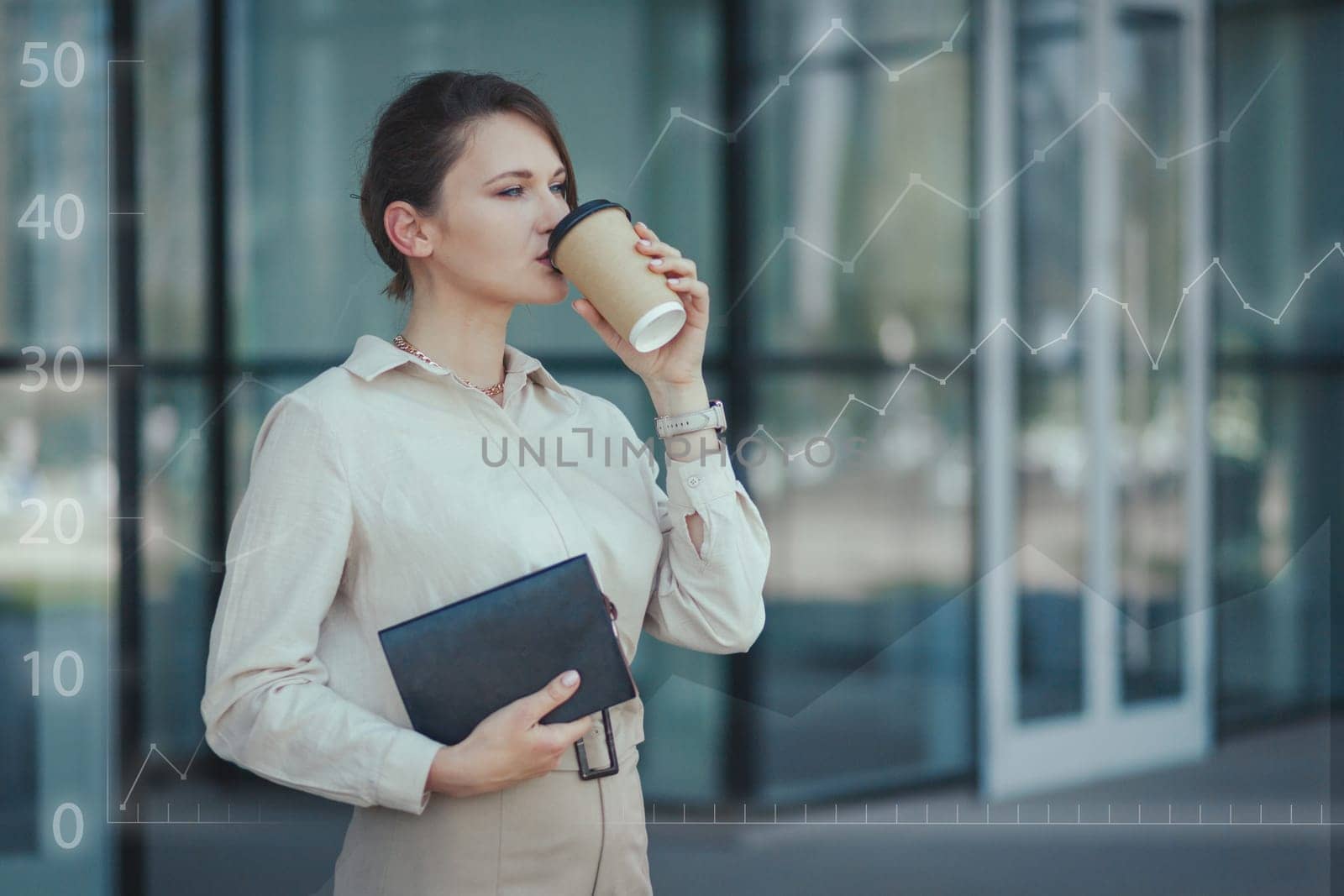 Young successful business woman manager drinks coffee against the background of growing profitable business indicators after adjusting automatic business processes.