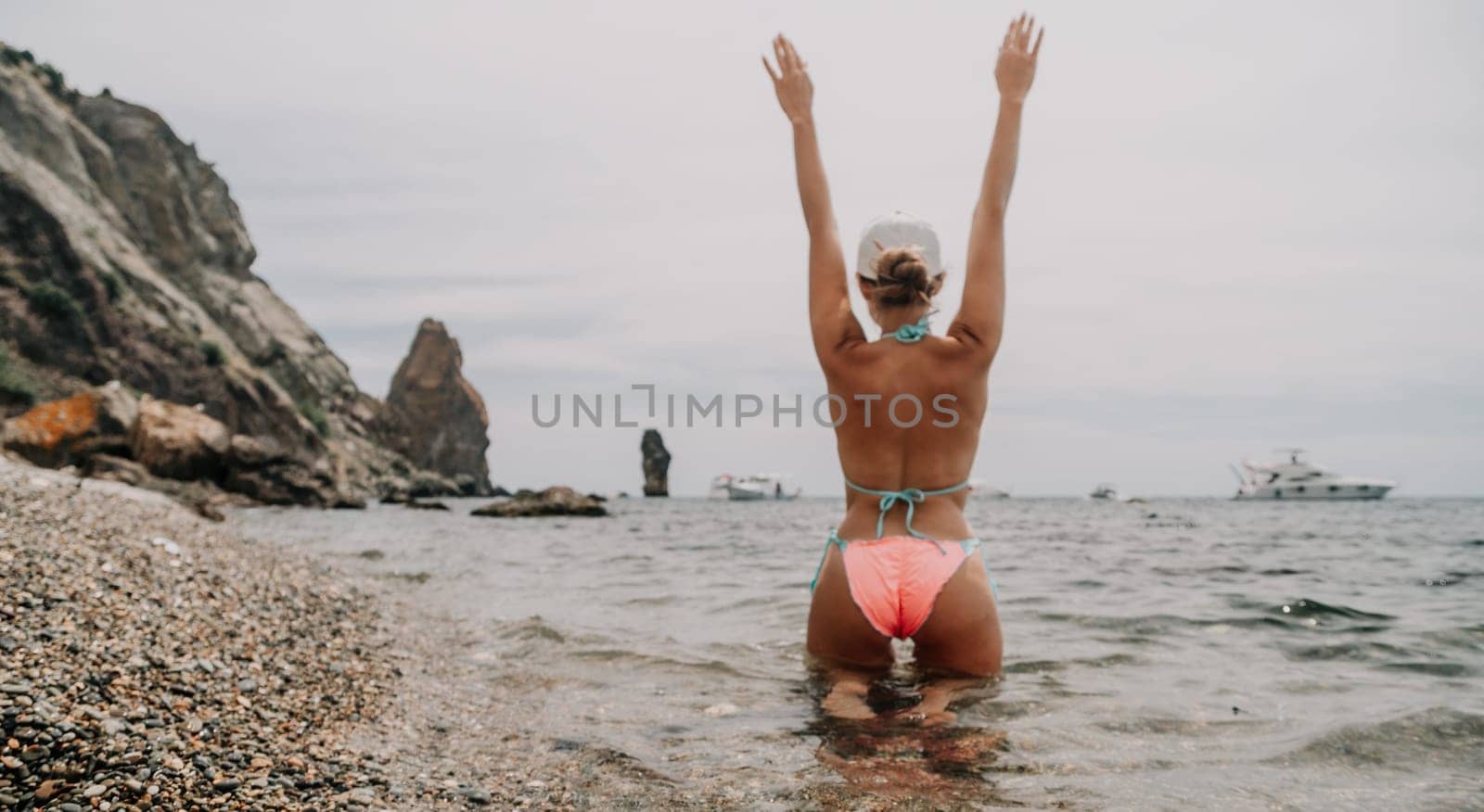 Woman travel sea. Happy tourist in pink bikini enjoy taking picture outdoors for memories. Woman traveler posing on the beach at sea surrounded by volcanic mountains, sharing travel adventure journey by panophotograph
