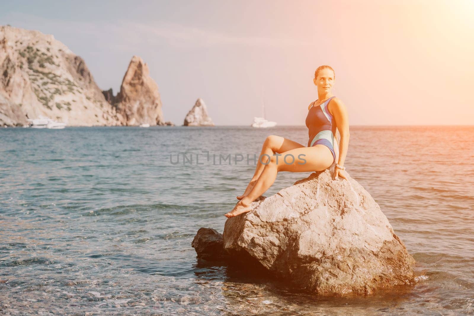 Woman travel sea. Happy tourist in blue swimwear takes a photo outdoors to capture memories. woman traveling and enjoying her surroundings on the beach, with volcanic mountains in the background. by panophotograph