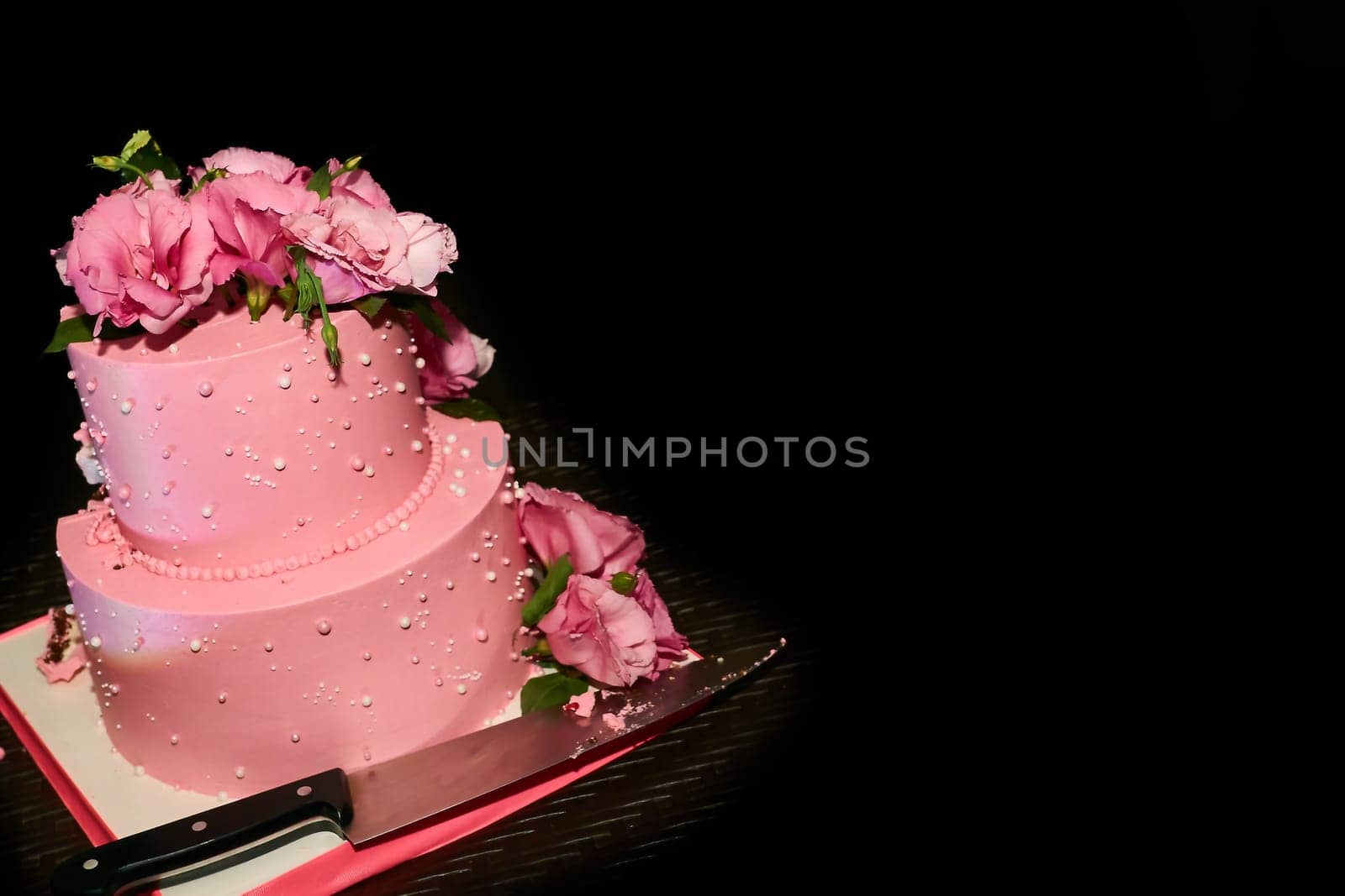 Cutting a delicious pink wedding birthday cake on a serving table by jovani68