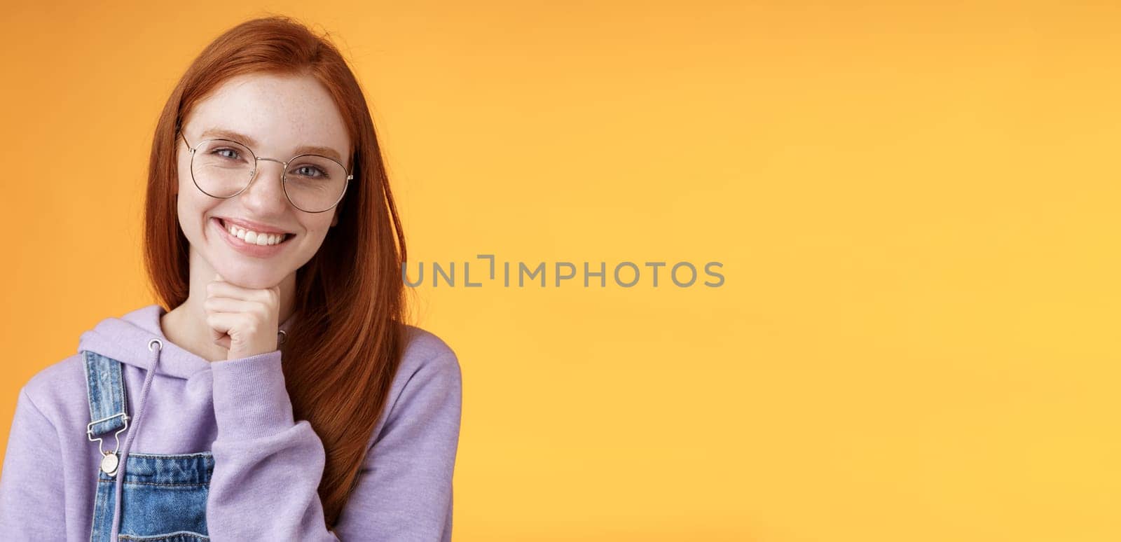 Creative outgoing young charismatic redhead female coworker discuss casual staff smiling laughing happily have pleasant conversation look camera amused tender touch chin, orange background.