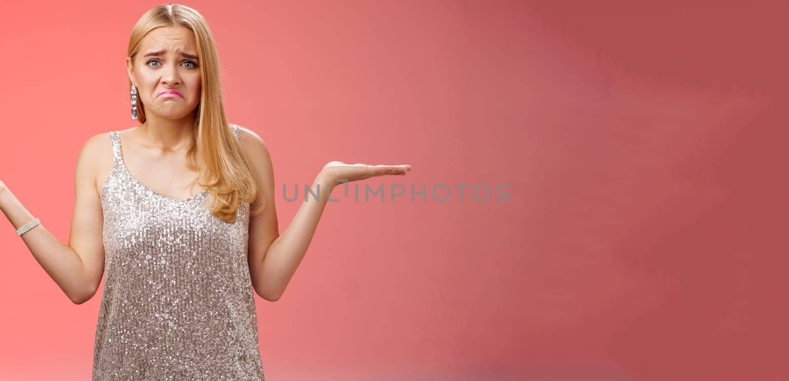 Upset clueless frustrated blond european young girl in glittering silver evening dress grimacing pouting sad shrugging raise hands sideways dismay doubtful, no idea what do, complicated decision.