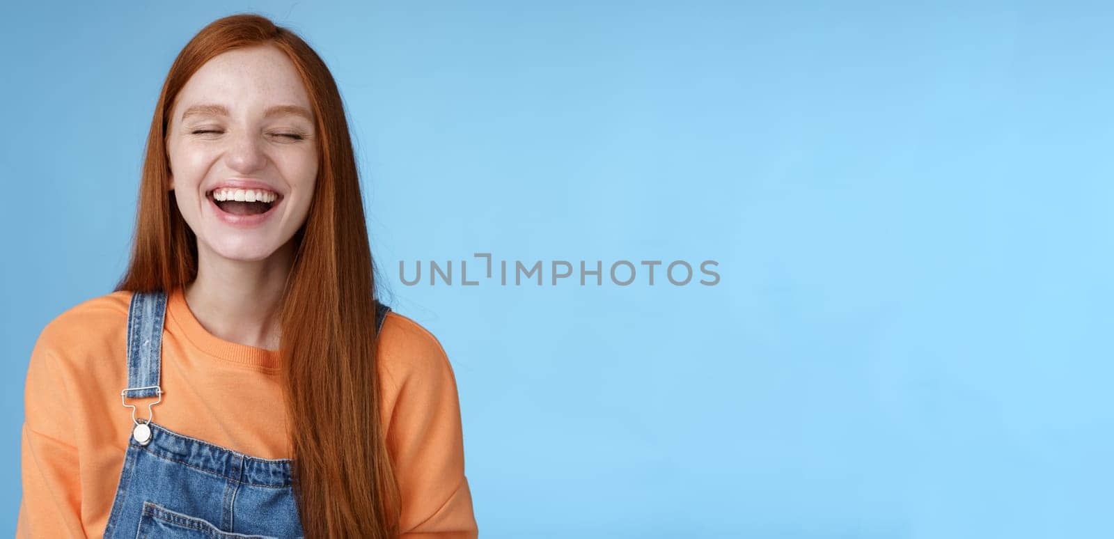 Carefree happy positive lucky redhead girl having fun close eyes smiling optimistic laughing out loud chuckling funny joke listen hilarious stories relaxing hang out friends, blue background by Benzoix