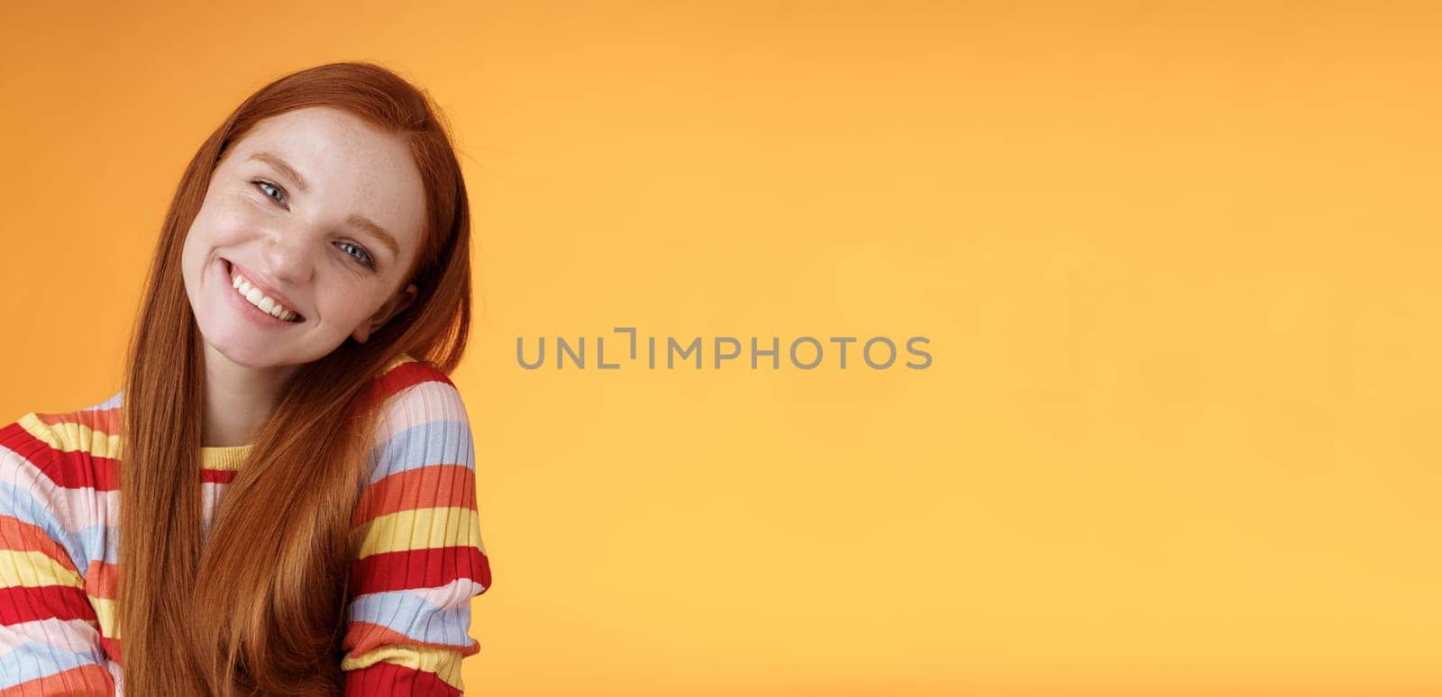 Lifestyle. Tender lively cheerful smiling redhead european girl 20s tilting head leaning shoulder flirting grinning cute make lovely gazes camera coquettish talking boyfriend standing silly orange background.