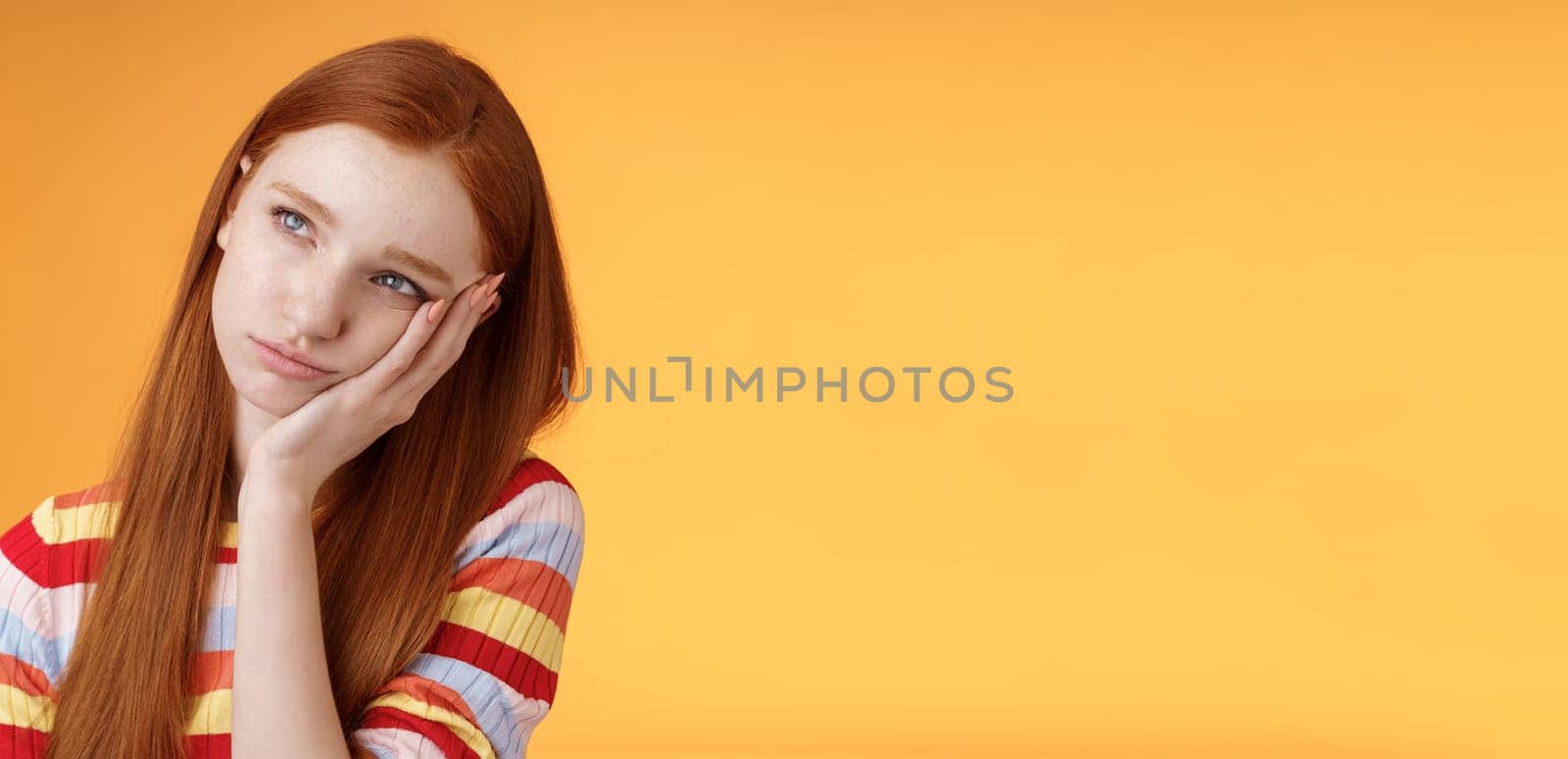 Lonely upset moody cute redhead girlfriend feeling boredom leaning palm look up pouting frowning displeased standing uneasy attend boring meeting, staring uninterested reluctant orange background by Benzoix