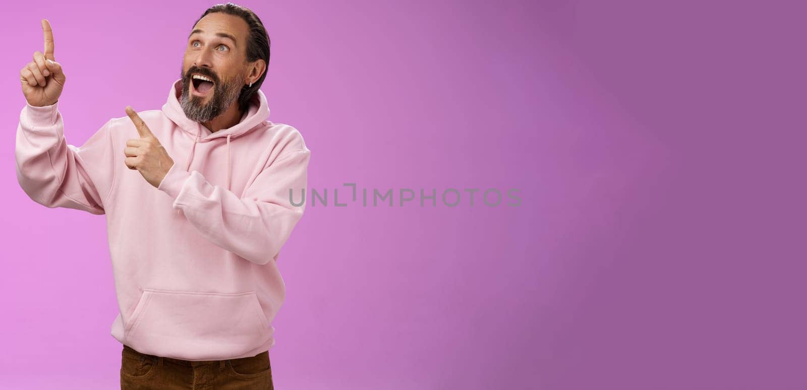 Fashionable good-looking fascinated mature bearded man grey hair look astonished pointing gazing upper left corner see miracle incredible breathtaking magnificanent view, standing purple background by Benzoix