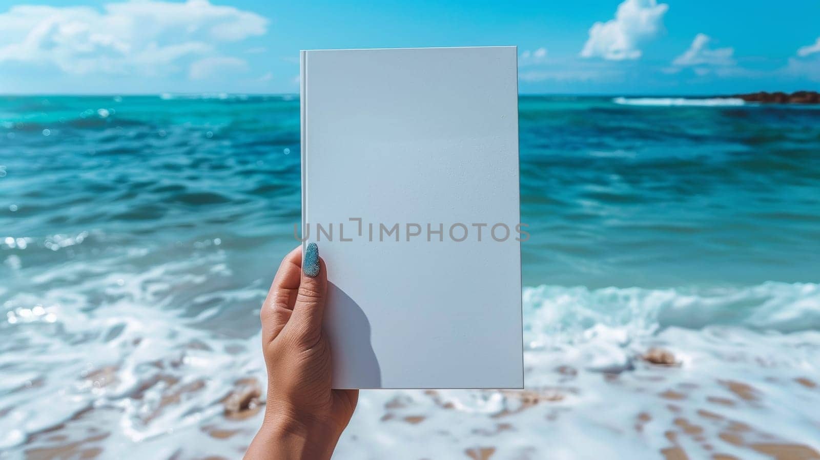 A person holding a blank book in front of the ocean