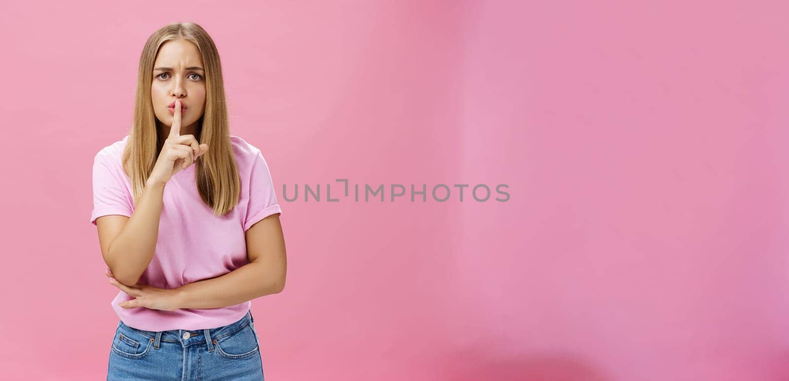 Shh keep voice down. Serious-looking concerned determined female nanny looking after kid asking not speak showing shush gesture with index finger over mouth, having secret concerned someone know it by Benzoix