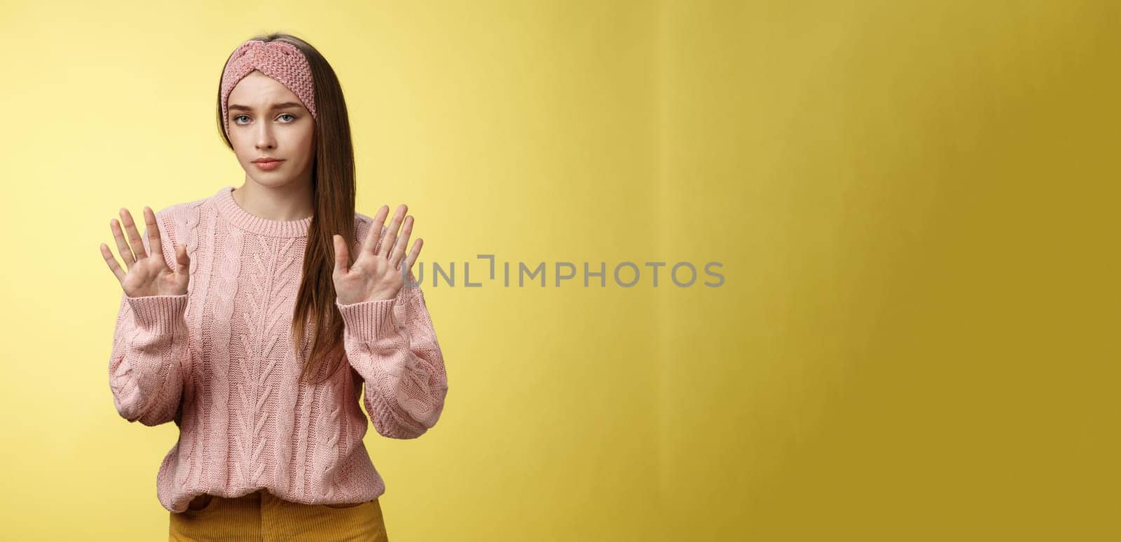 No thanks. Cute unamused picky young girl in knitted sweater, headband showing hold on, slow down, refusal gesture raising palms in rejection being reluctant unimpressed and indifferent to proposal.