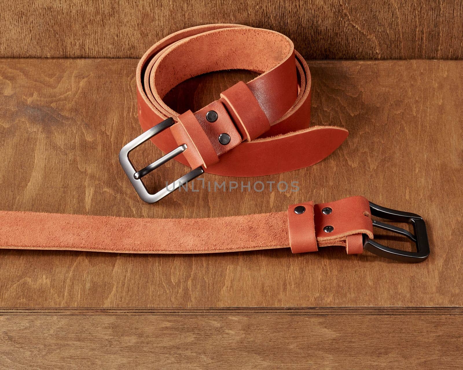 Wooden stand featuring two terracotta leather belts with DAD embossment on loop and humorous inscription engraved on reverse side. Stylish personalized handmade accessories
