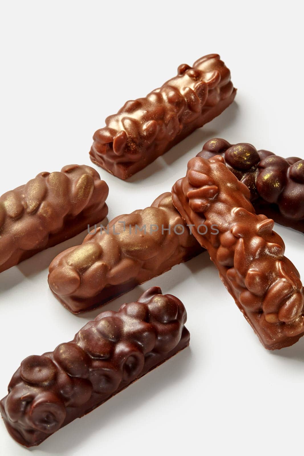 Variety of milk and dark chocolate bars with almonds, peanuts and hazelnuts, displayed against white background. Popular sweet snack concept