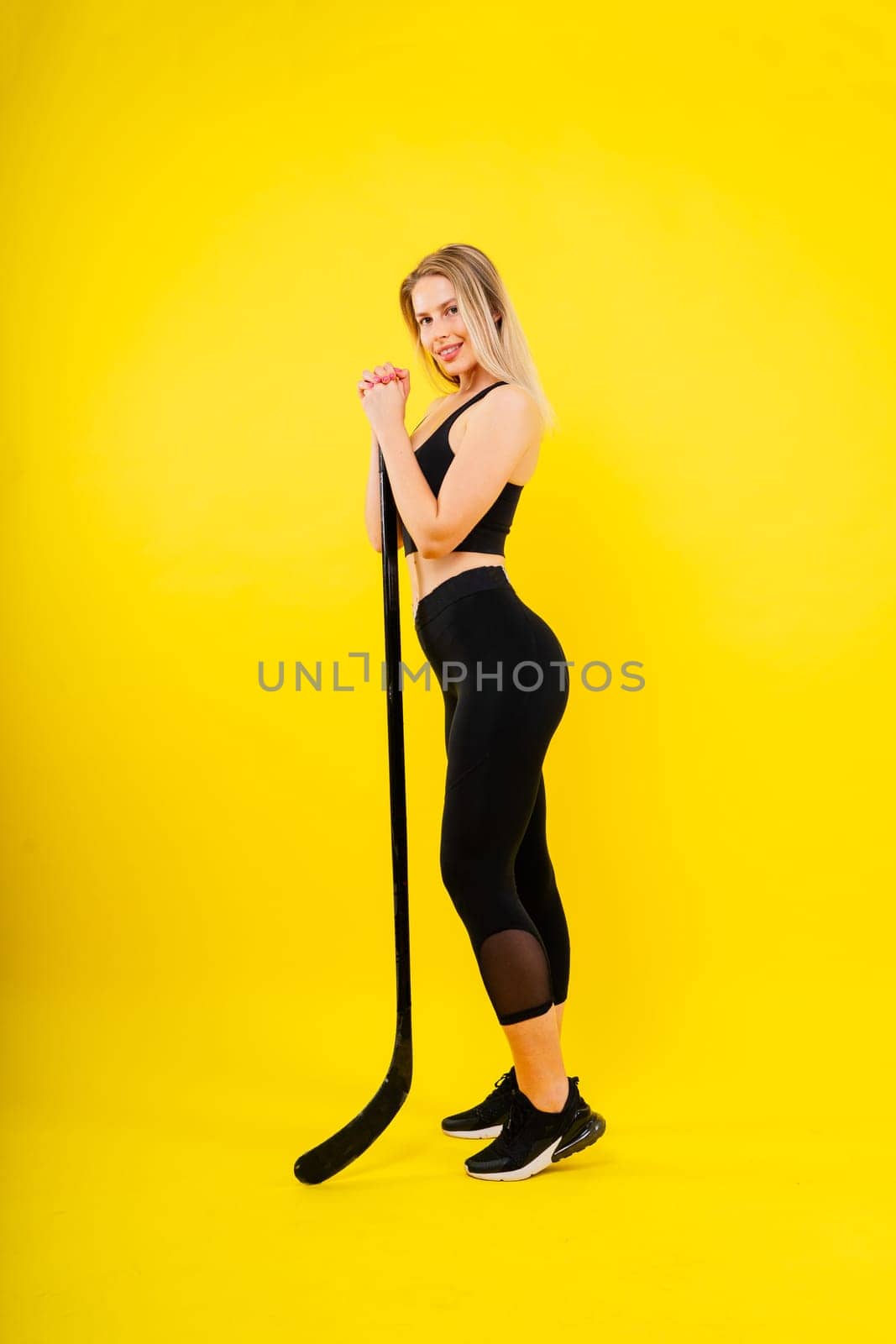 Ice hockey fan female in sports wear with hockey stick in a studio