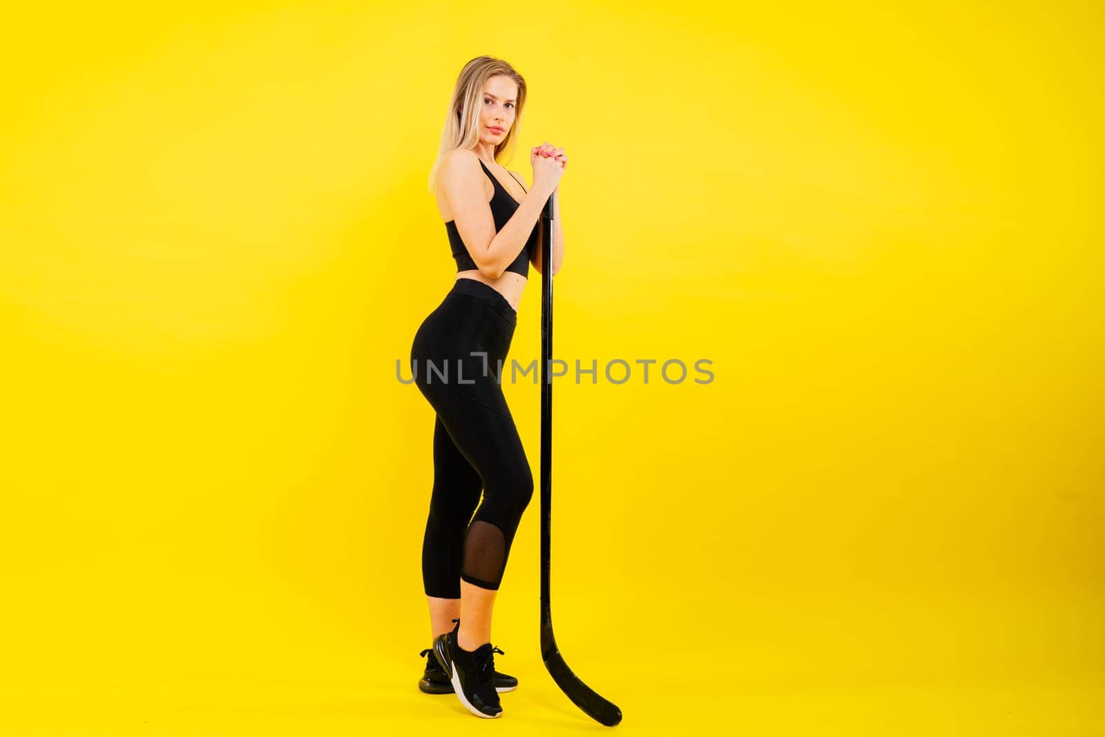 Ice hockey fan female in sports wear with hockey stick in a studio