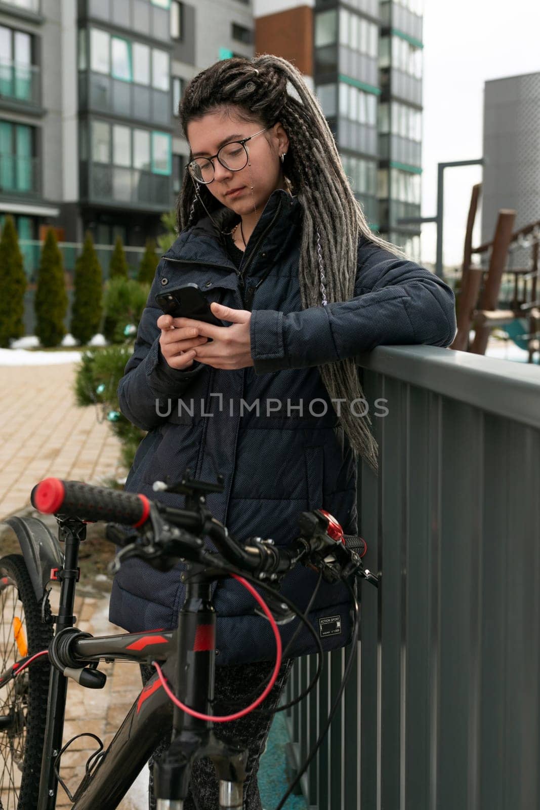 A pretty young woman with a dreadlocked hairstyle rides a bicycle and stops to rest.