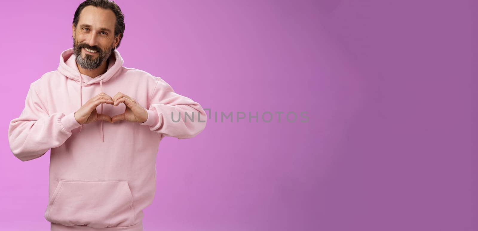 Family in heart. Portrait lovely handsome romantic bearded man in pink hoodie passionatly looking camera show love gesture smiling cute expressing romantic sympathy attitidue, purple background by Benzoix