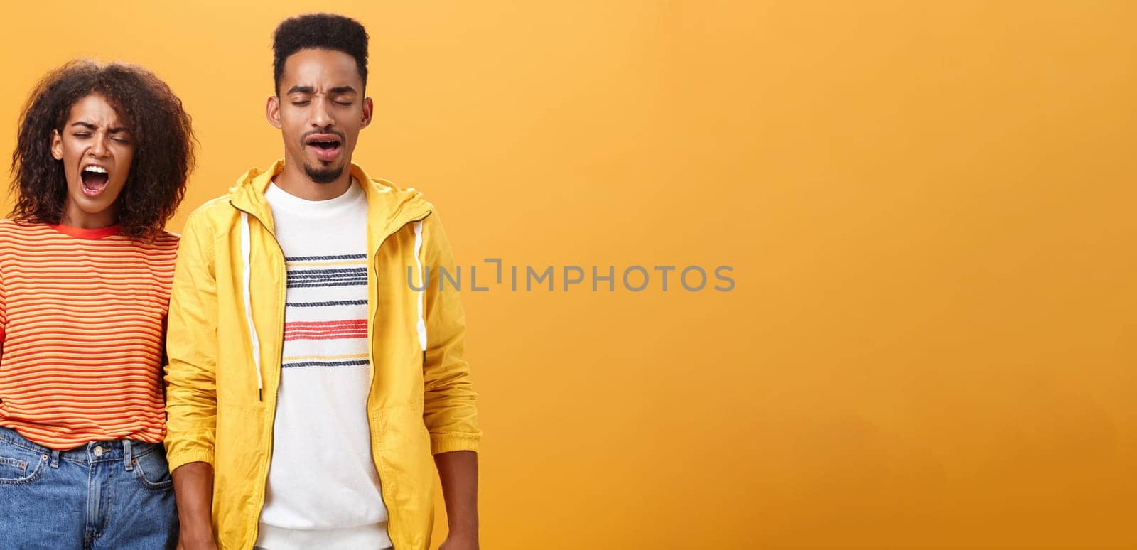 Stylish and attractive brother and sister over orange background yawning with closed eyes and tired expression being drained and exhausted after dealing with house chores cleaning mess after party. Lifestyle.