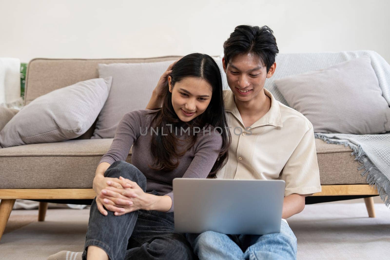 Happy asian couple using laptop sit relax on floor doing ecommerce shopping online on website at home.