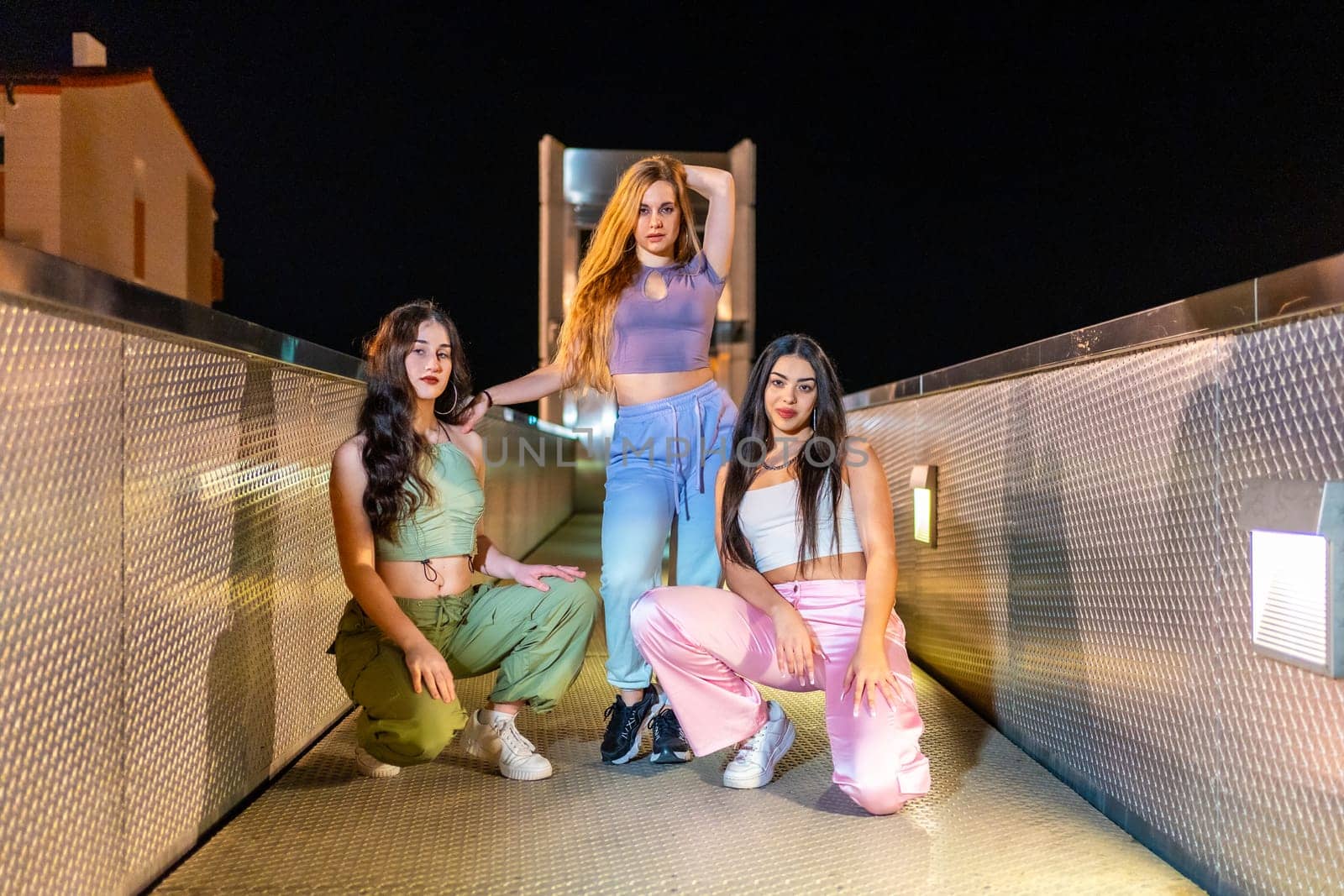 Three female young trap dancers posing together on a bridge at night