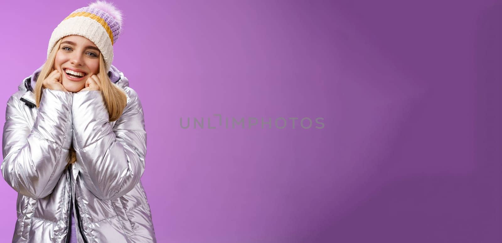 Delighted charming tender female in stylish cute hat silver shiny jacket lean chin hands smiling sighing enjoying watching lovely romantic scene wanna fall in love standing happily purple background by Benzoix