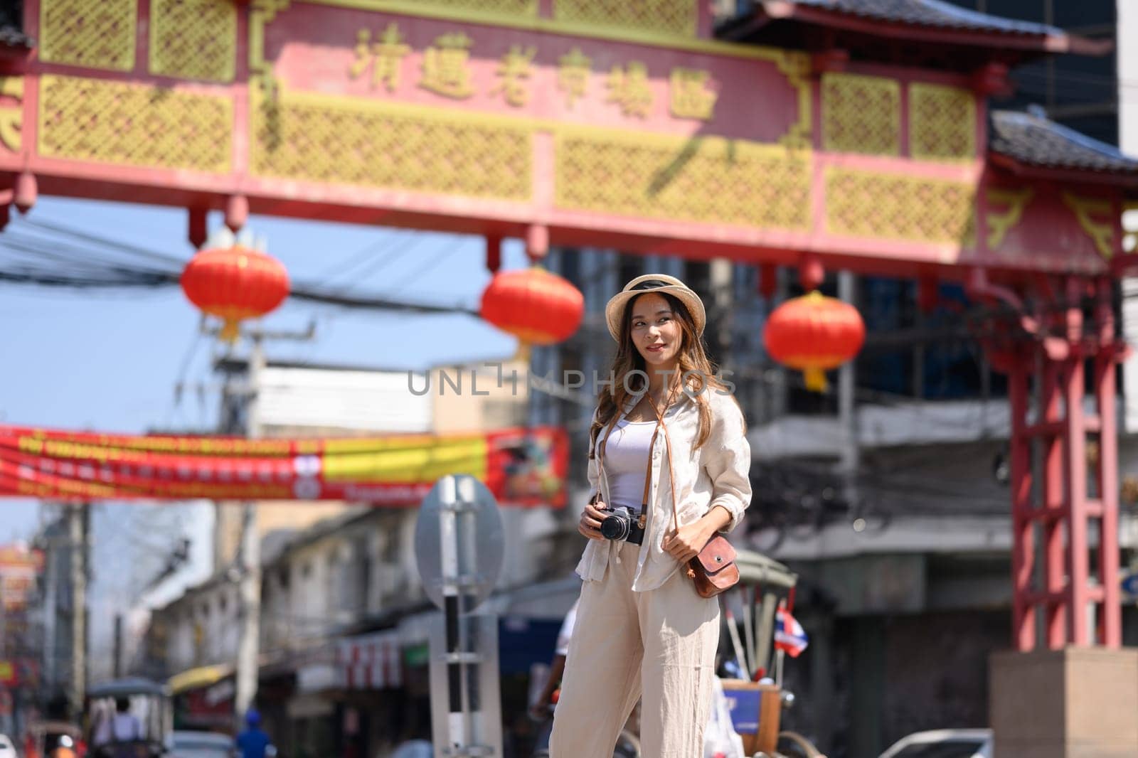 Portrait of smiling young woman walking at Chinatown street with beautiful red lanterns adorning.