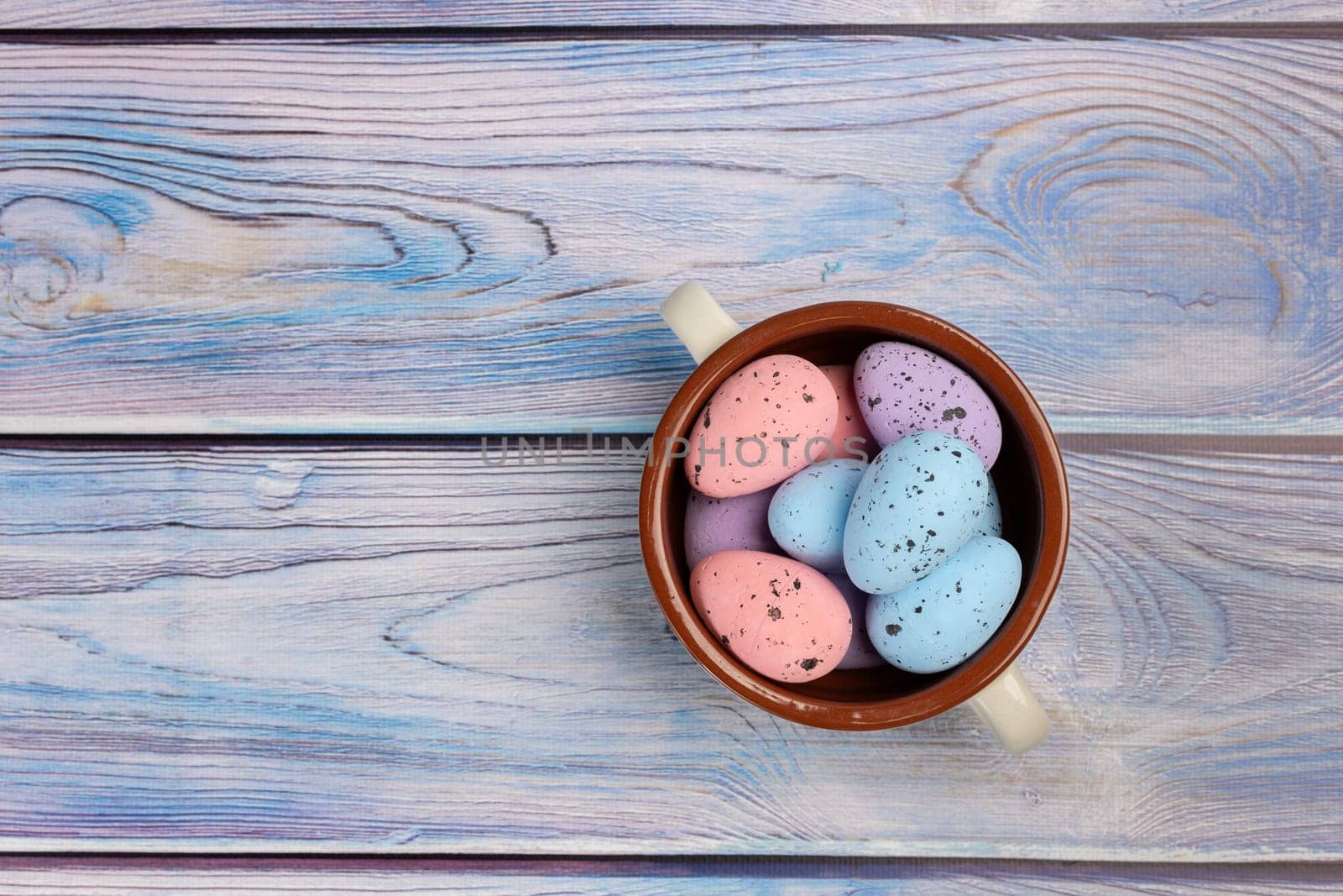 Bowl with colored Easter eggs on the wooden boards. Top view.