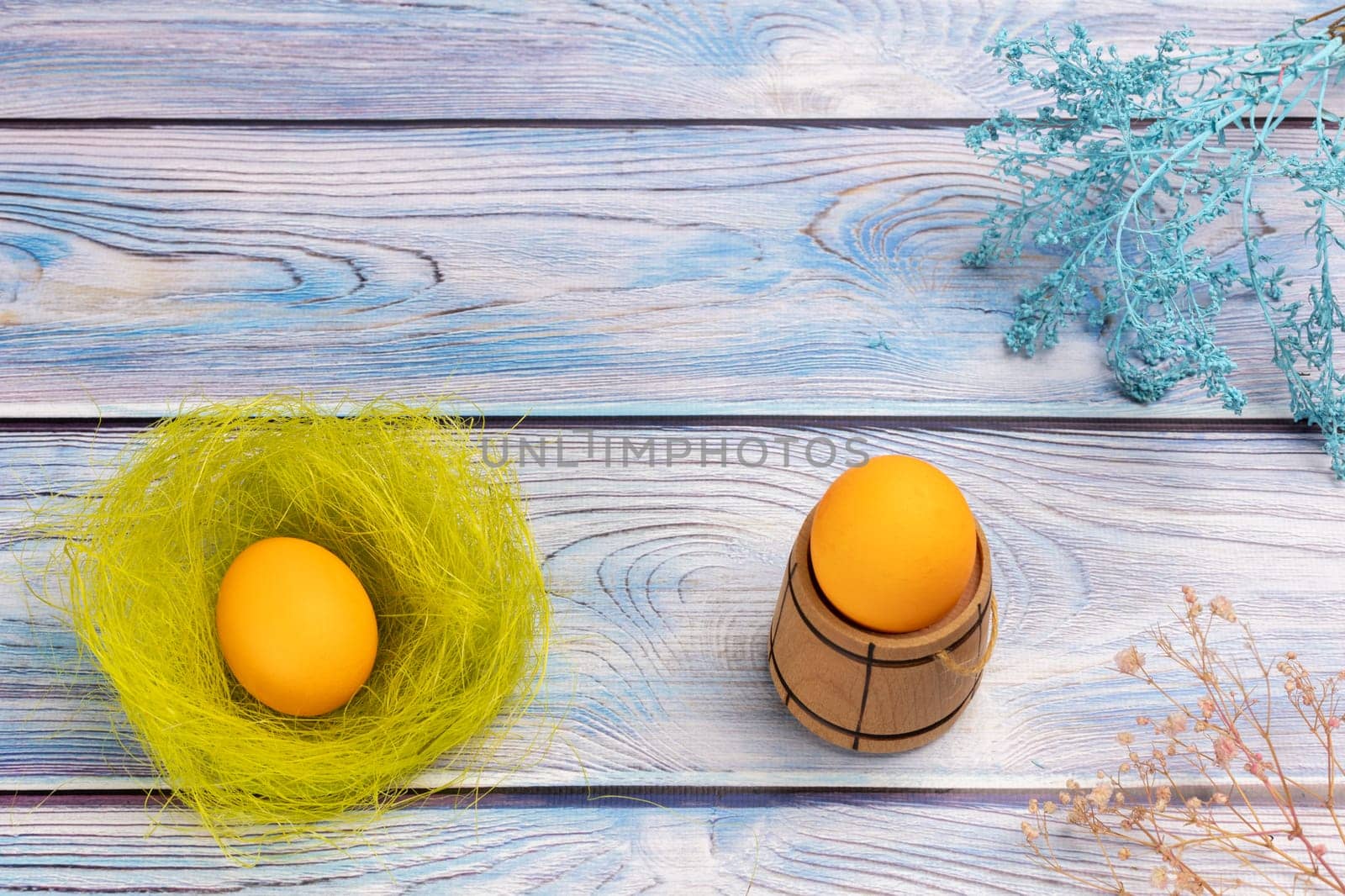 Nest with Easter egg and a small wooden barrel with an egg on the boards with decorative plants. Top view.