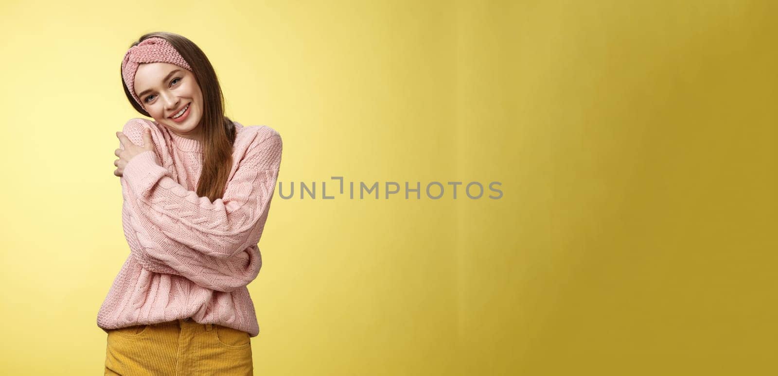 Girl feeling warm and safe thanks charming boyfriend embracing herself romantically hugging leaning on shoulder enjoying warmth of fluffy sweater, smiling tender in love over yellow background by Benzoix