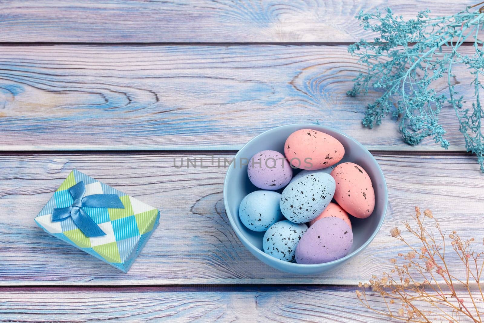 Bowl with colored Easter eggs and a gift box on the wooden background. by mvg6894