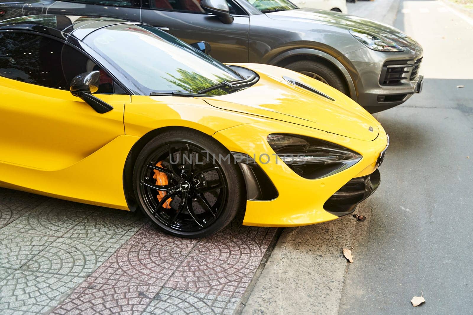 Ho Chi Minh City, Vietnam - 05.07.2023: a yellow sports car is parked next to a black sports car by driver-s
