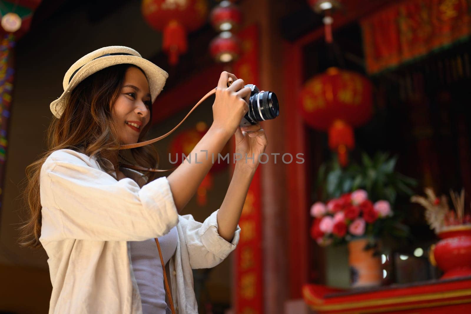 Attractive female tourist taking photo with her camera at Chinatown district in Chiang Mai, Thailand by prathanchorruangsak