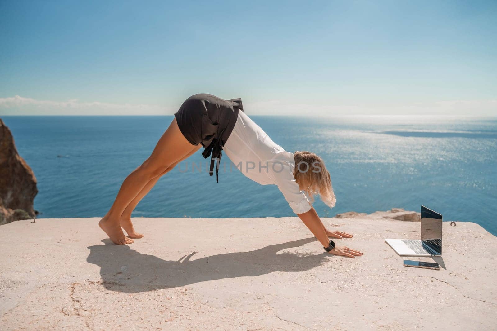 Freelance women sea working on the computer. Good looking middle aged woman typing on a laptop keyboard outdoors with a beautiful sea view. The concept of remote work