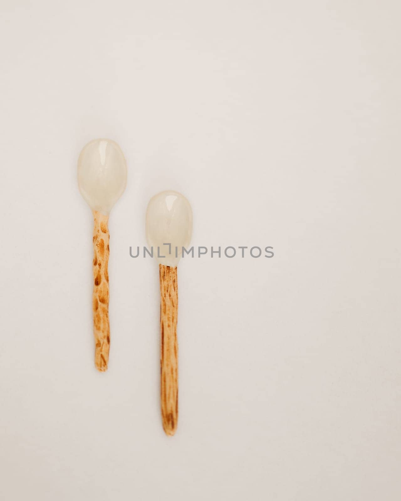 Two Unique Ceramic Spoons with Wooden Handles on a White Surface by apavlin