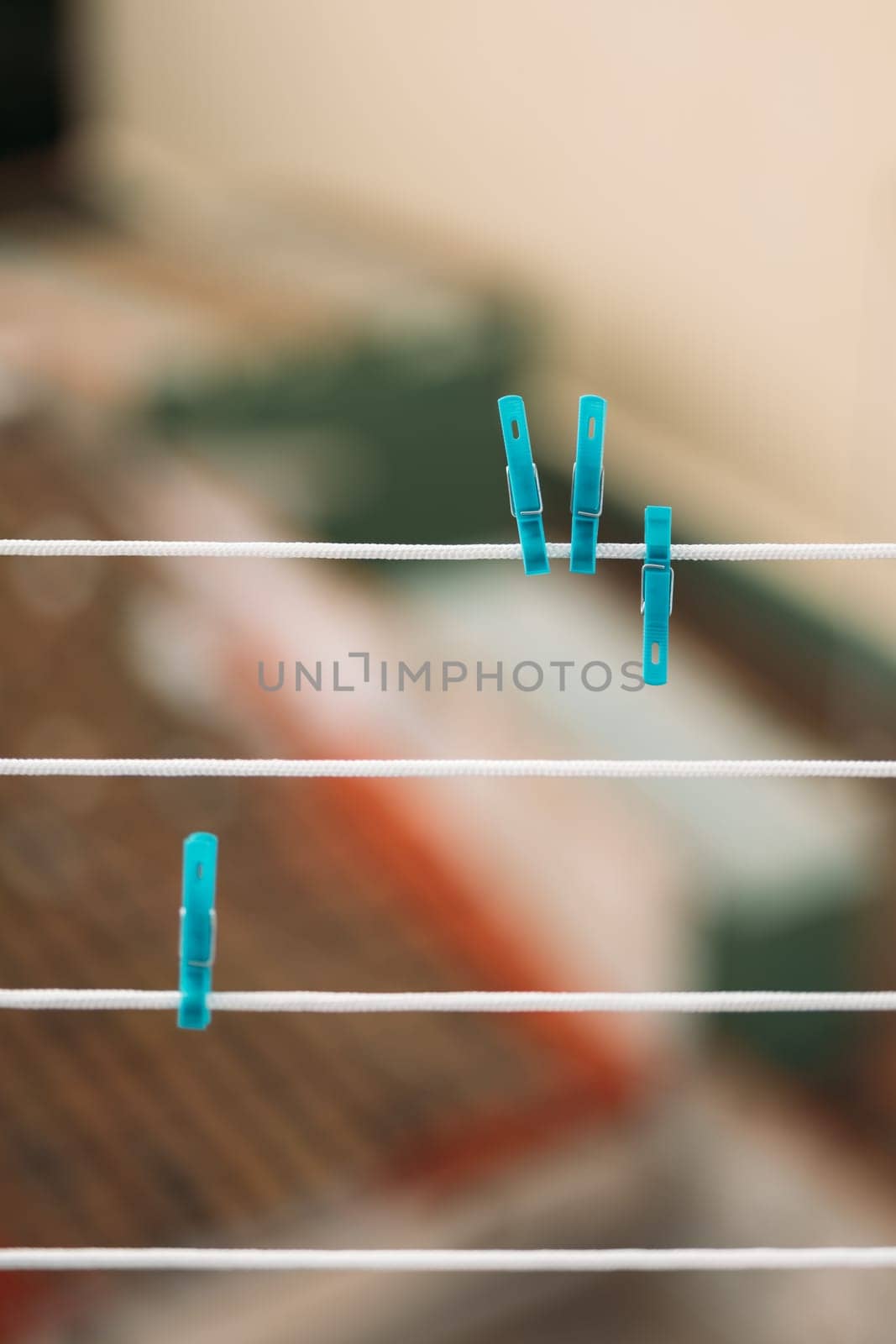 Selective focus image of blue clothespins clipped to a white clothesline with blurred background