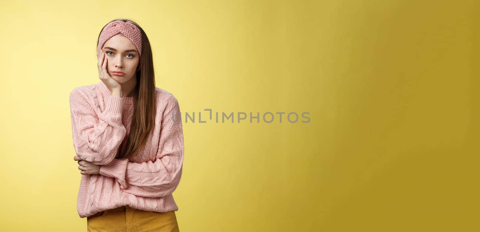 How boring. Indifferent upset gloomy girl missing party feeling bored leaning on palm reluctant, sad looking careless at camera visiting uninteresting lecture, suffering boredom over yellow wall.