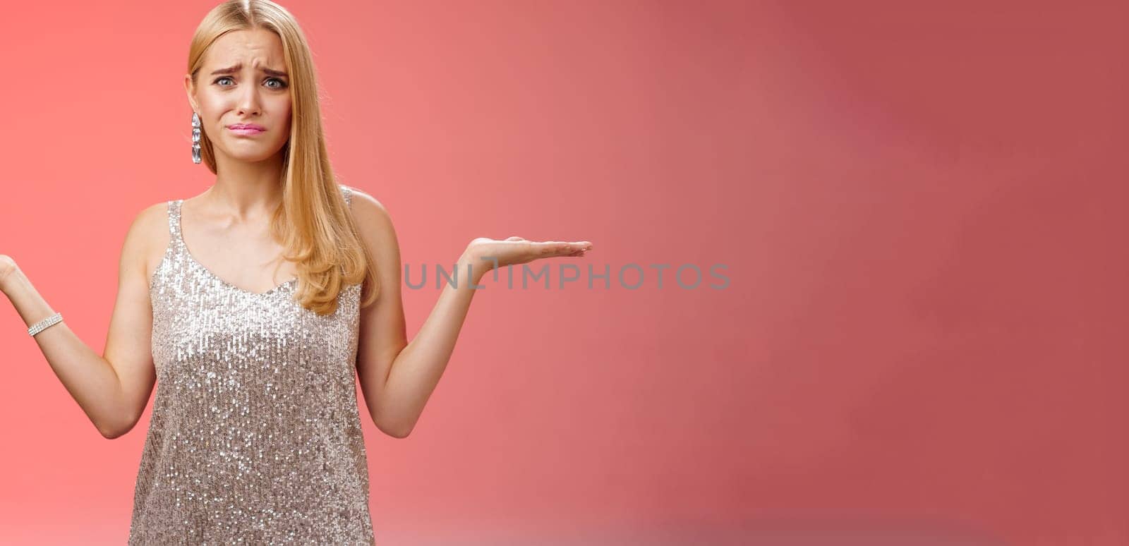 Nervous unsure doubtful cute blond woman struggle make decision shrugging pointing sideways frowning upset standing insecure feel pressure cannot decide choice make, frustrated red background.