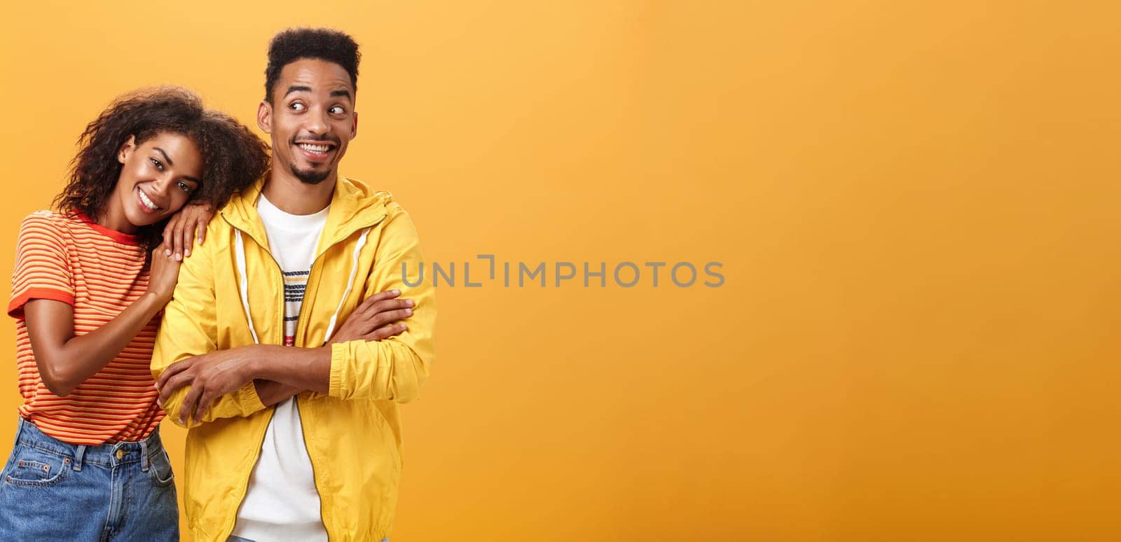 Guy feeling happy girl lean on his shoulder grinning and chuckling from happiness standing pleased and joyful over orange background while woman hugging best friend upbeat she can rely on him. Relationship concept
