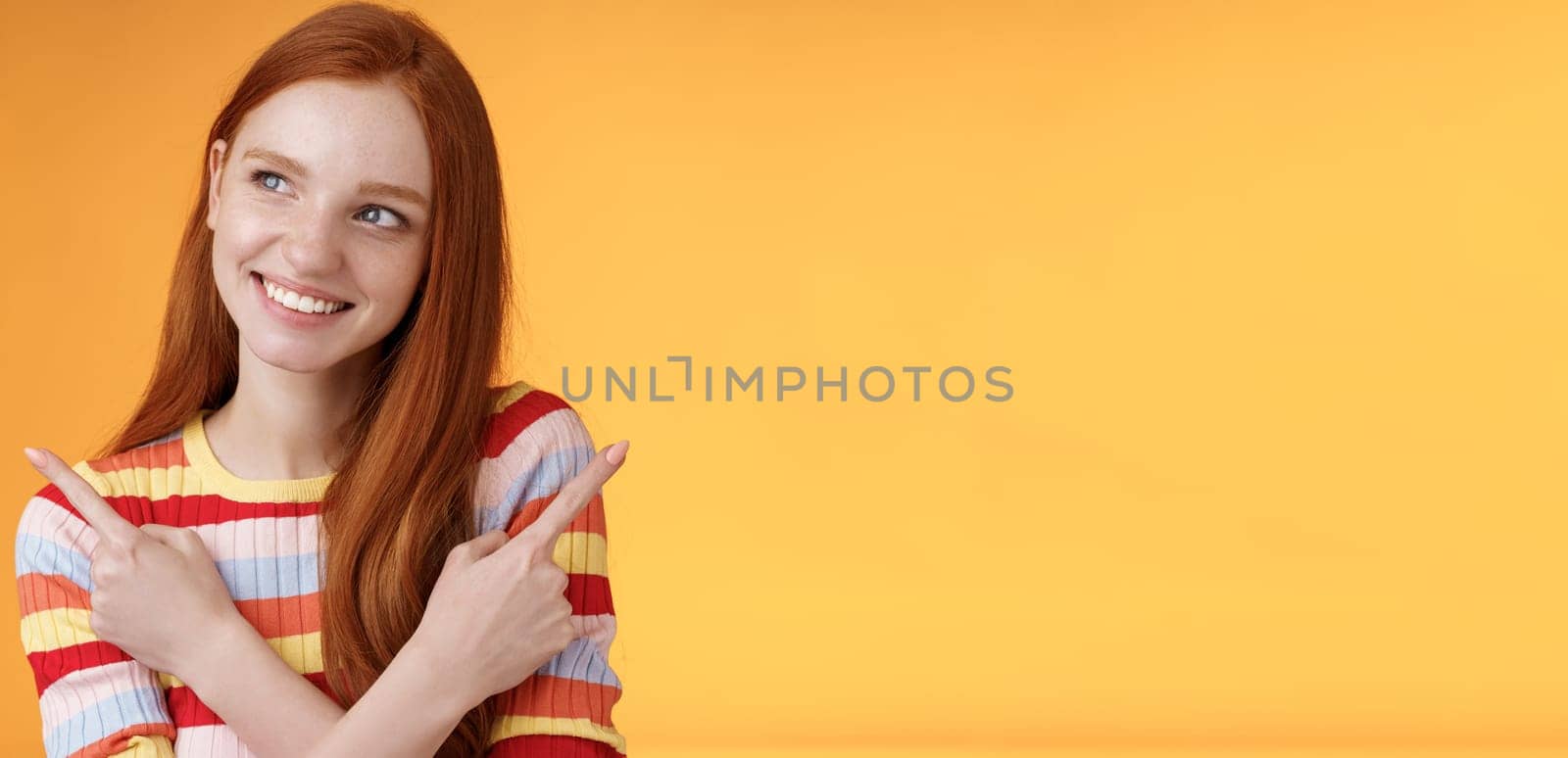 Dreamy cute redhead girl planning were go summer holidays have different choices picking variant look intrigued smiling pleased pointing sideways left right taking decision, orange background by Benzoix