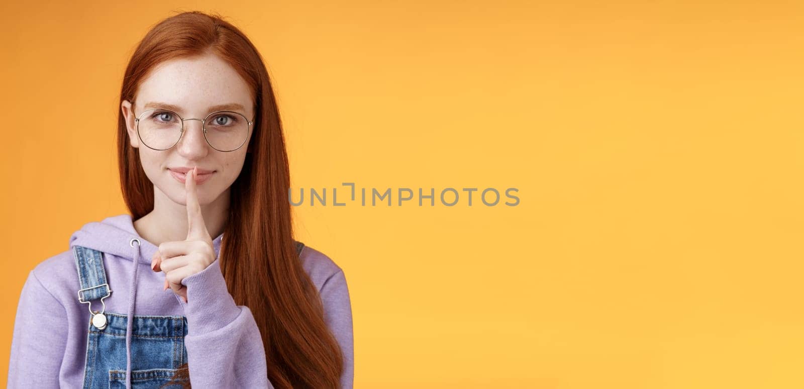 Shh secret safe. Young sensual mysterious redhead attractive woman hiding info say shush silence quiet please prepare surprise hold index fingers mouth taboo, standing orange background by Benzoix