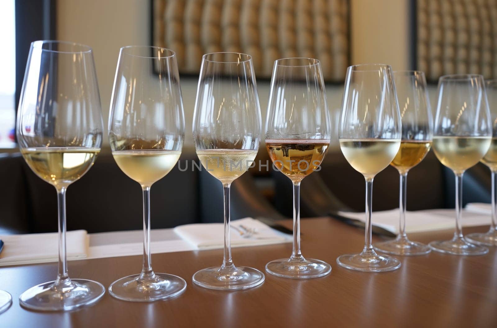 A set of glasses with different shades of white wine are neatly arranged on a polished wooden table for wine tasting