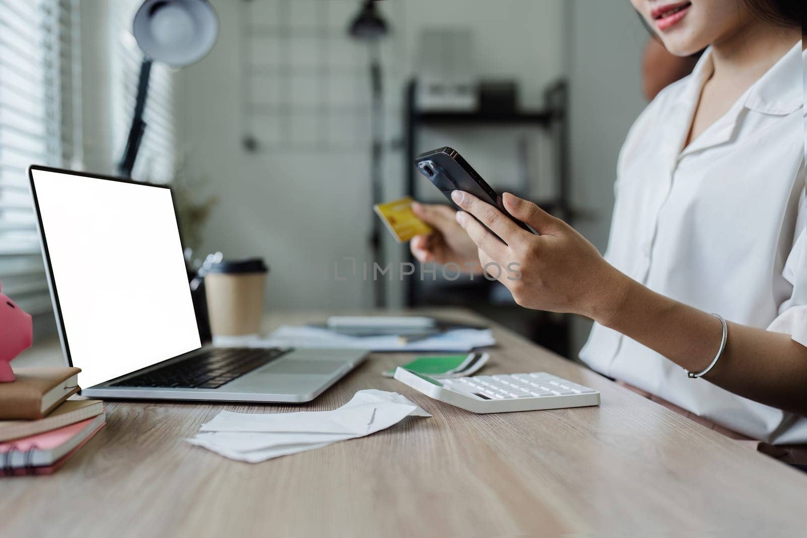 Young woman makes a purchase on the Internet on the laptop with credit card and mockup laptop blank screen.