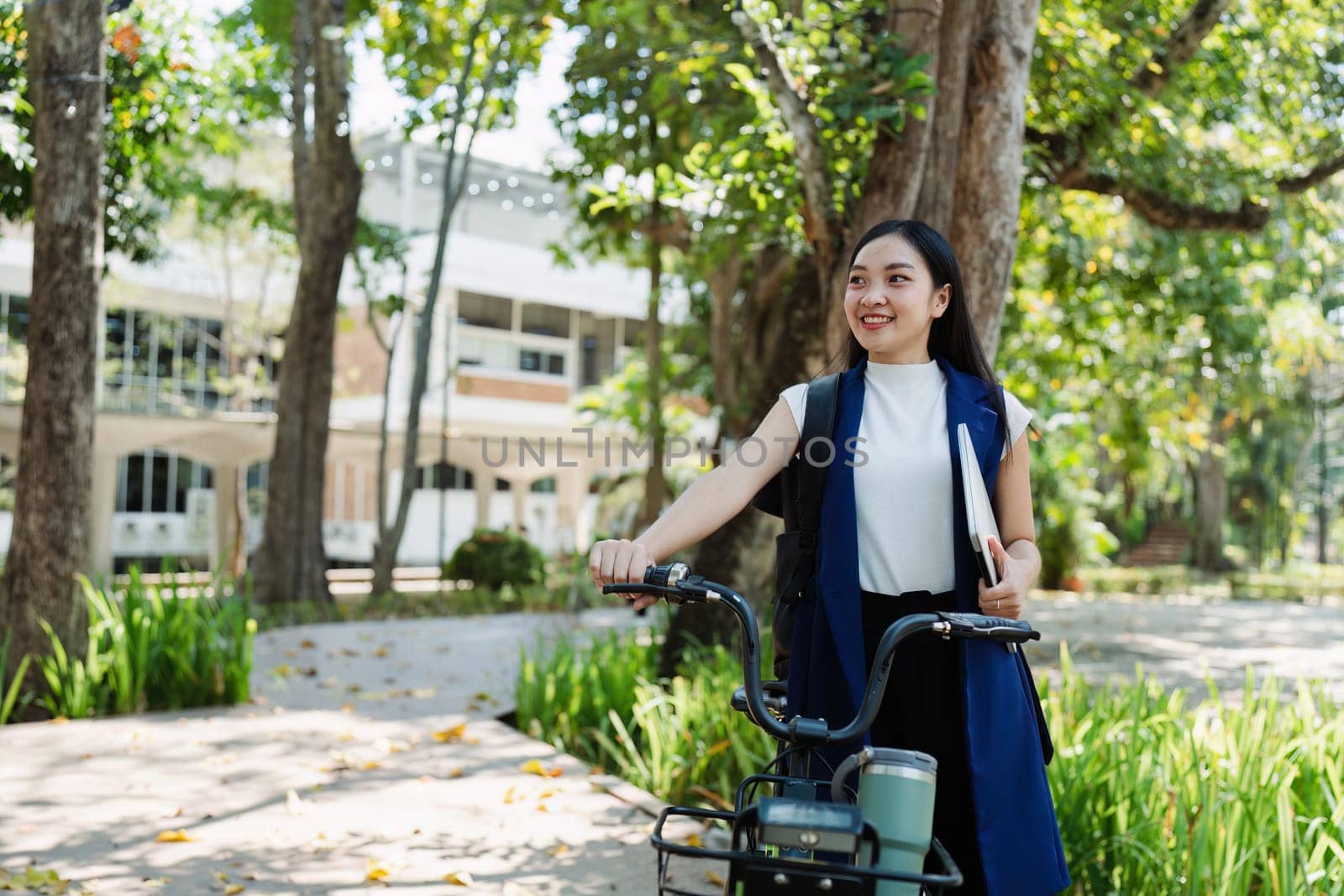 Young businesswoman sitting on stair in city park and using laptop for work hybrid. Bike to work eco friendly alternative vehicle green energy by itchaznong
