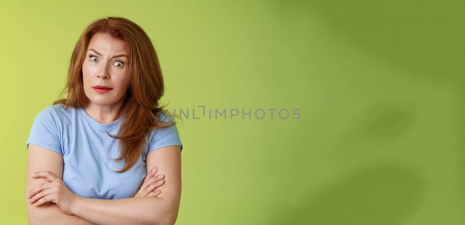 You did what. Confused shocked speechless redhead mature mother stare camera puzzled concerned cross arms chest self-soothing bothered pose look questioned hesitant green background by Benzoix