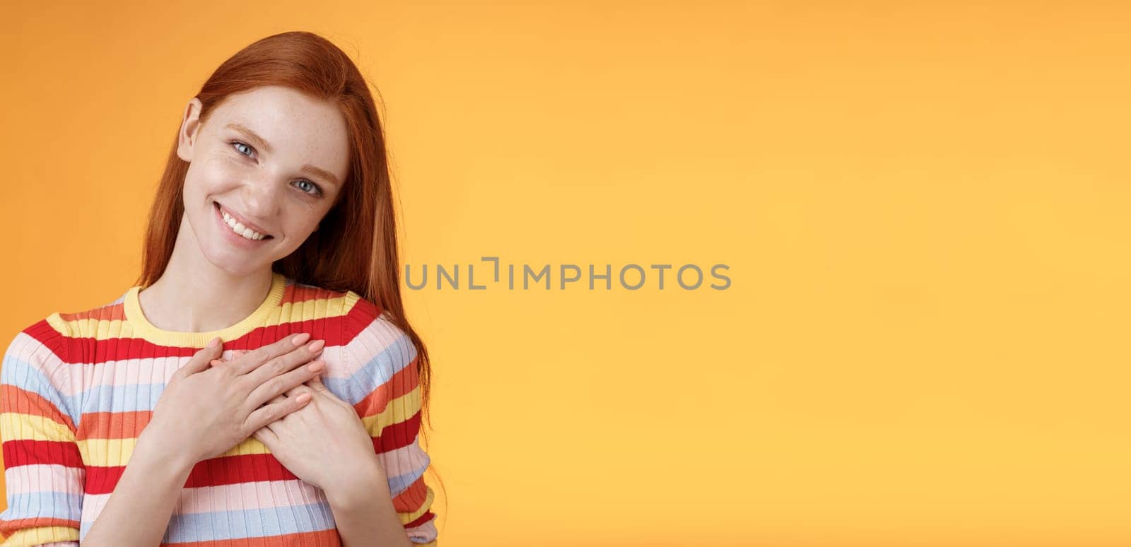 Pleased tender feminine good-looking redhead woman receive compliment confession touch heart feel warmth dearest moment smiling delighted lovely keep love inside soul, standing orange background.