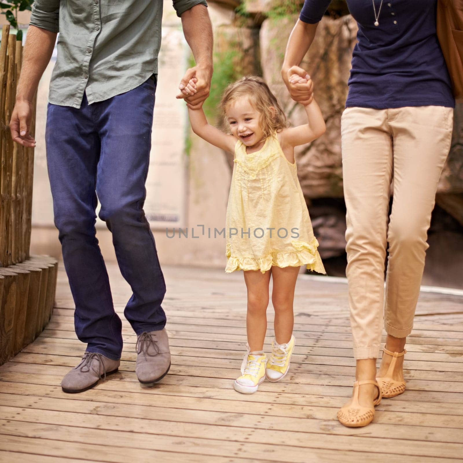 Happy, little girl and holding hands with parents for bonding, adventure or field trip. Excited child or kid walking with mom and dad in travel for fun holiday, weekend or sightseeing together.
