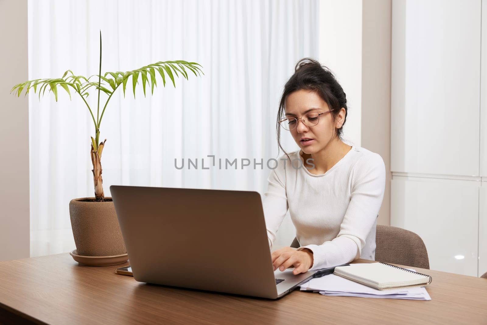 pretty woman in glasses using laptop at home by erstudio