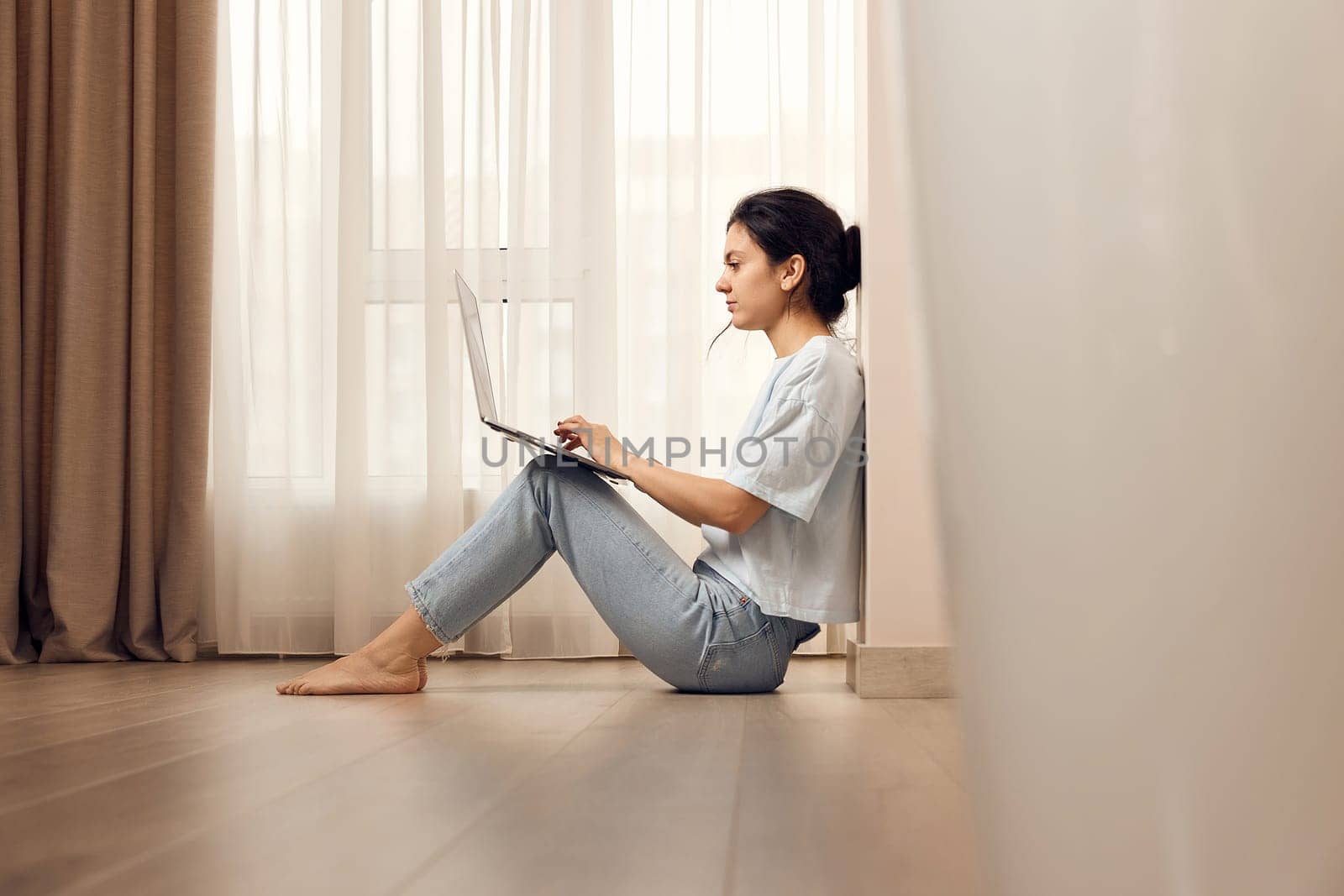 casual woman sitting on the floor and working on laptop at home